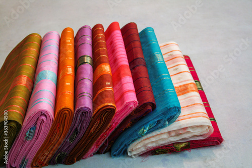 Maheshwari saris in a textile shop, displayed in front of customers. Maheshwar, Madhya Pradesh, India. photo