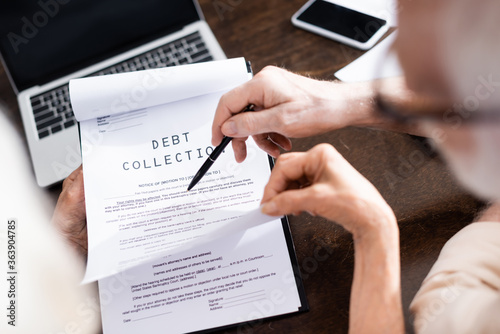 Fotografie Selective focus of senior man holding pen near wife with debt collection letteri