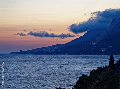 Sea sunset against the background of the village lights and fog descending from the mountains