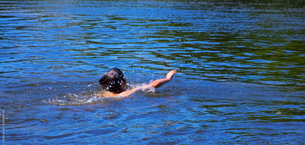 happy boy learn to swim crawl on a blue lake, holidays, summer experiences, relaxation, natural background