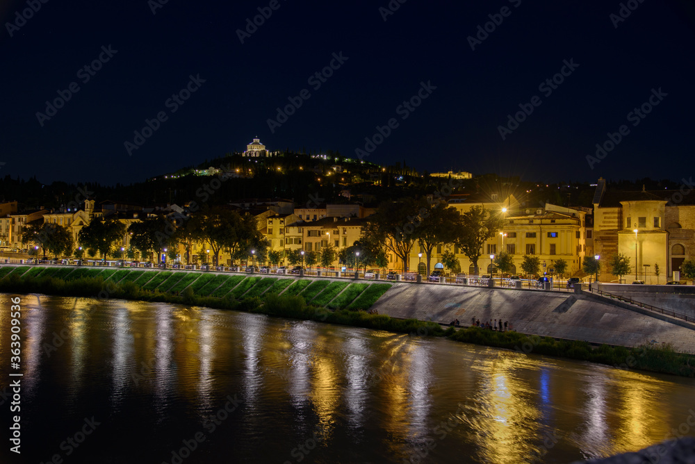 Night photo along Adige river along Lungadige San Giorgio street with view of the church of the sanctuary of the Madonna of Lourdes, city of Verona, Italy.