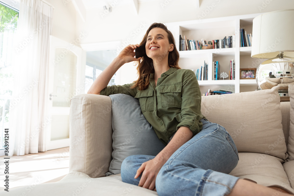 Woman talking on smartphone while sitting on couch at home Woman talking on smartphone while sitting on couch at home
