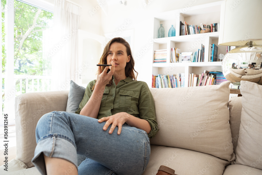 Woman talking on smartphone while sitting on couch at home Woman talking on smartphone while sitting on couch at home