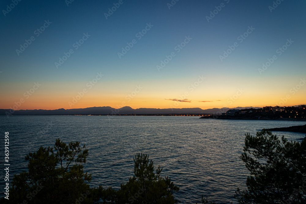 A beautiful sunset in a coast of Salou (Spain) with a blue sky and rocks