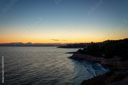 A beautiful sunset in a coast of Salou (Spain) with a blue sky and rocks