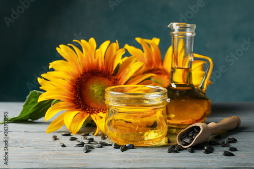 Composition with sunflower, seeds and oil on gray wooden background