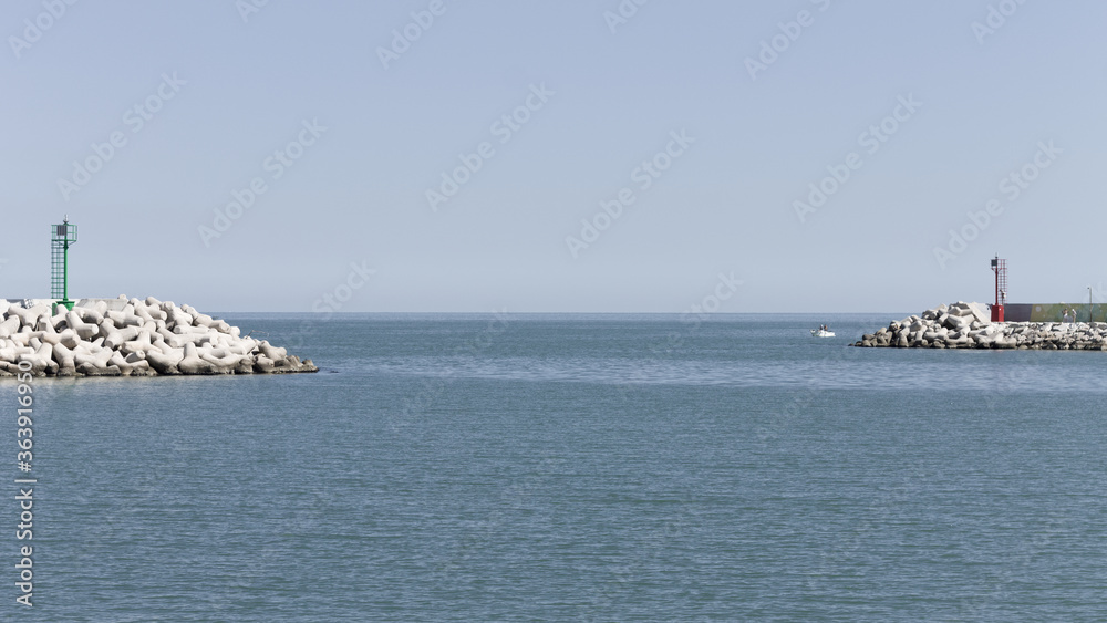 The entrance of Pesaro harbour with tetrapod breakwaters, and a green and a red lighthouse on the piers (Marche, Italy, Europe)