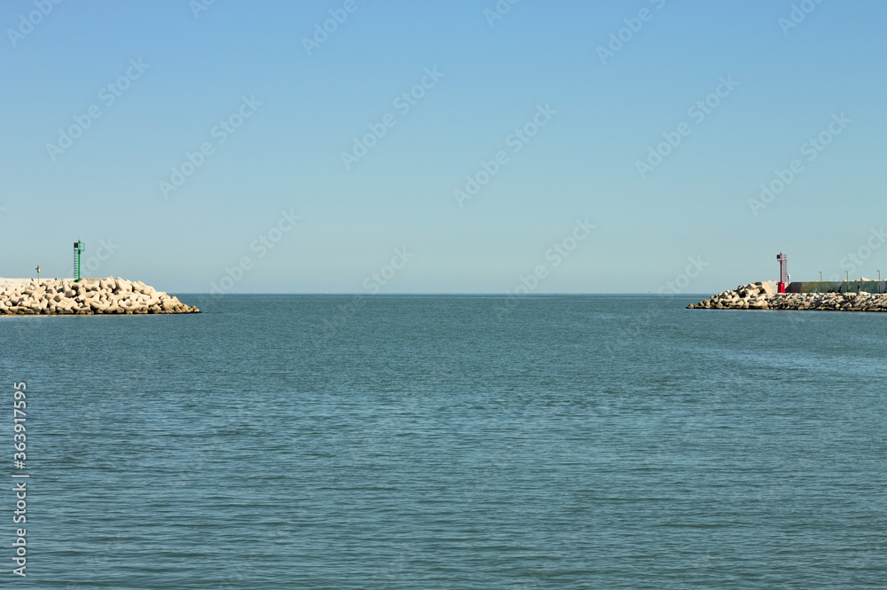 The entrance of Pesaro harbour with tetrapod breakwaters, and a green and a red lighthouse on the piers (Marche, Italy, Europe)