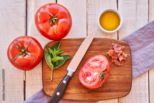 Top view of a cut tomato on a wooden board. Mediterranean food and healthy diet.