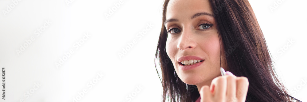 Beautiful girl manager holds pen face and smiles Beautiful girl manager holds pen face and smiles