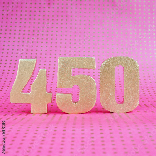 450 golden volumetric digit on a bright pink polka dot background. copy space..