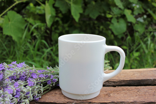 Cup of coffee with milk or cappuccino and lavender flowers on wooden board in summer garden. Enjoying morning coffee. Top view, copy space. Selective focus