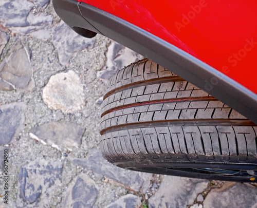 Una ruota sotto sterzo di una macchina rossa: pneumatico con battistrada rivolto verso l’esterno.  photo
