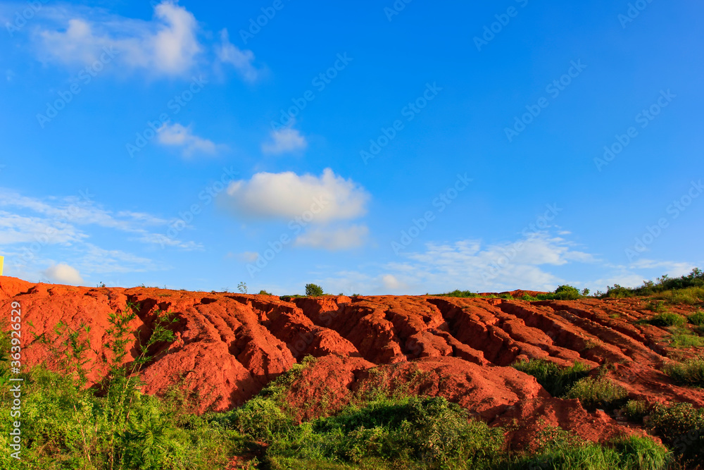 Naklejka premium The red land is under the blue sky and white clouds.