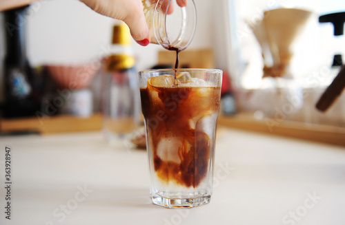 Making espresso tonic. Pouring espresso into glass with tonic and ice