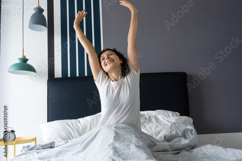 Beautiful girl wakes up in a good mood in a stylish apartment. Stretches with a smile starting the day