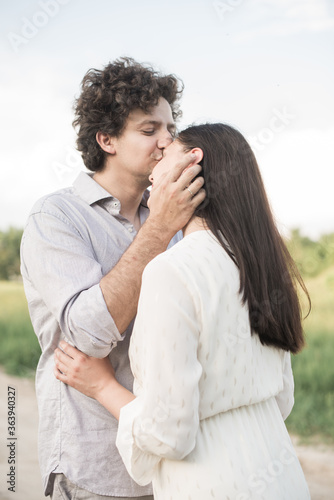 Young man gently kissing girlfriends head. Soft selective focus.