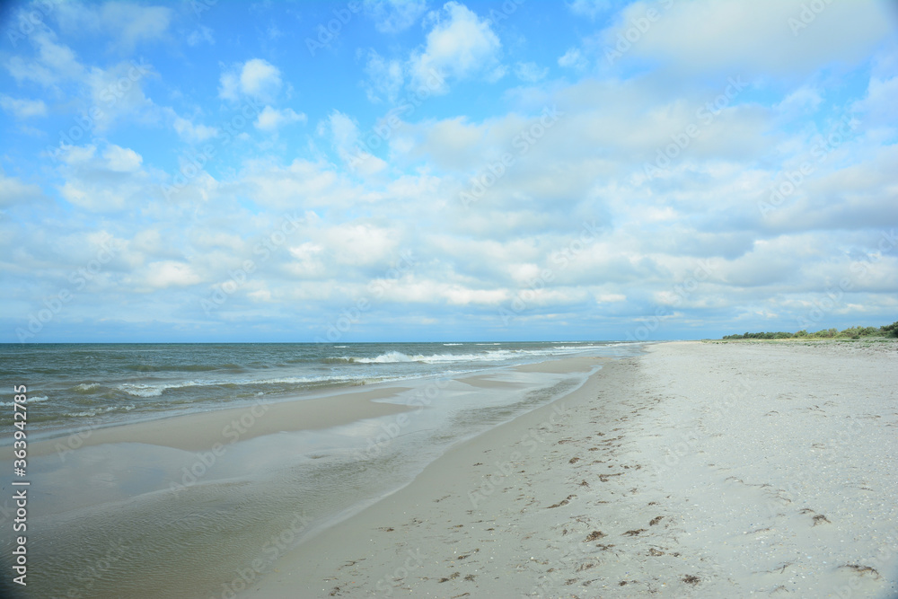 Beautiful seascape with a dark blue sea, long coast line, sandy beach and blue sky on a sunny day.