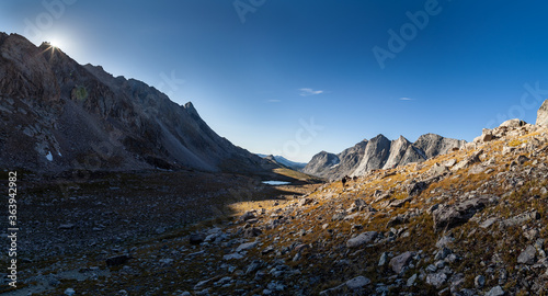 A backpacker ascends Raid/Bonneville Pass as the sun rises over the peaks to the east. Wind River High Route in Wyoming’s Wind River Range.