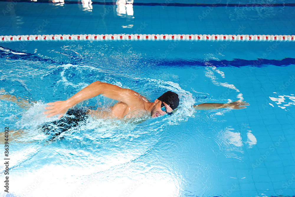 Man swimmer is swimming in the pool. Freestyle stroke, front crawl stroke. Swimming in blue pool, side view. breathing technique during swimming