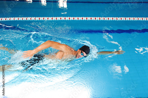 Man swimmer is swimming in the pool. Freestyle stroke, front crawl stroke. Swimming in blue pool, side view. breathing technique during swimming