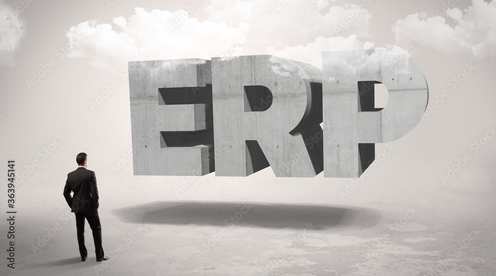 Fototapeta premium Rear view of a businessman standing in front of ERP abbreviation, modern technology concept