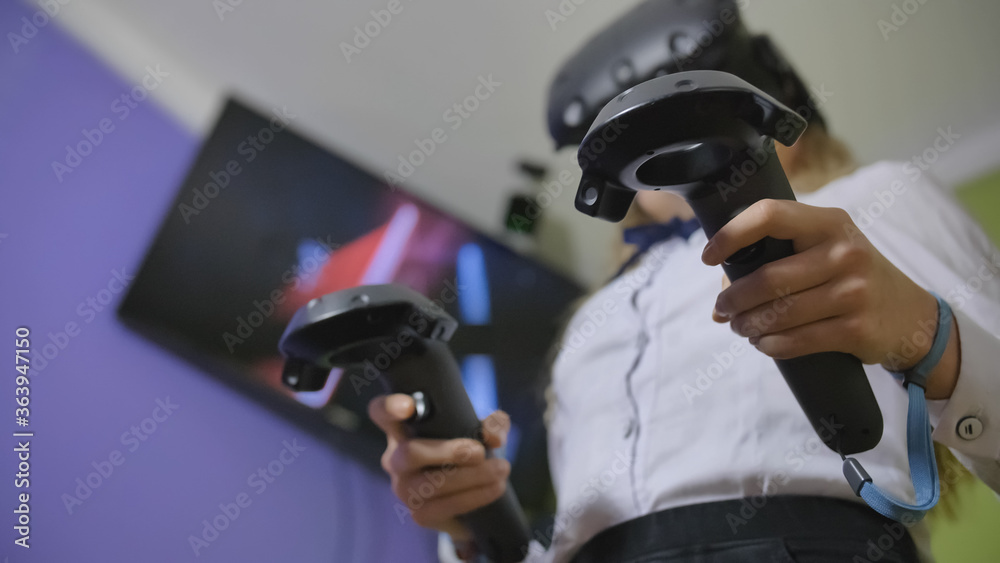 A teenage girl plays a virtual game in black virtual reality glasses. A teenage girl plays a virtual game in black virtual reality glasses.