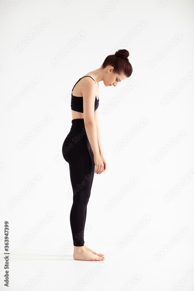 Sporty yoga girl on white background stretching in pose Adho Mukha Svanasana, downward-facing dog Pose, downward dog, down dog. Concept of healthy life and natural balance. Full length