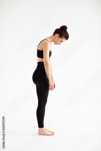 Sporty yoga girl on white background stretching in pose Adho Mukha Svanasana, downward-facing dog Pose, downward dog, down dog. Concept of healthy life and natural balance. Full length