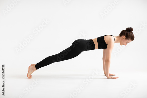 Sport, yoga and people concept, young woman doing plank, taking a balance. Full length profile side photo of sporty woman make plank exercise want become muscular healthy person. isolated on white.
