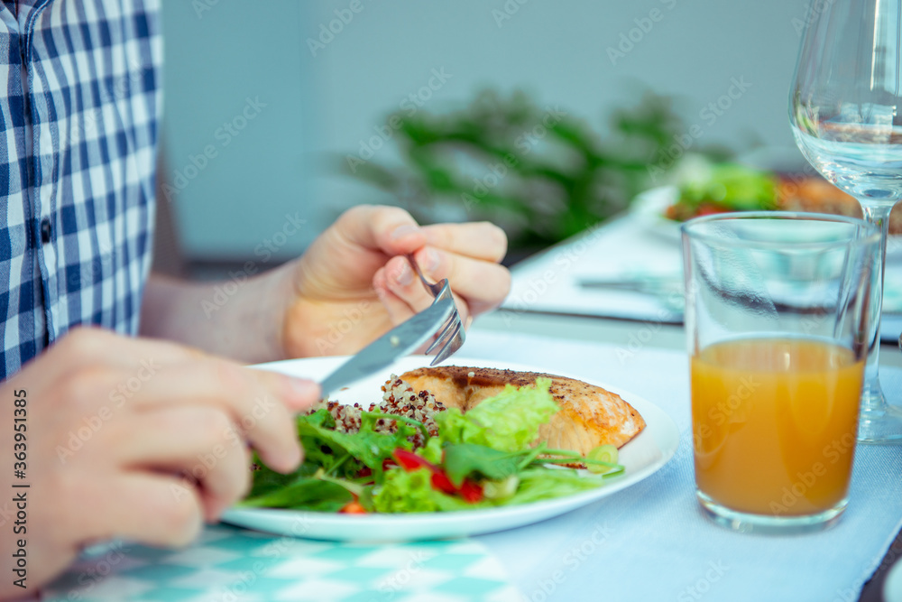 Close up photo of hands man eating salad, quinoa and fish on terrace Close up photo of hands man eating salad, quinoa and fish on terrace