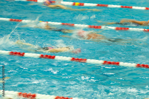 Competitive swimmers warm up in a pool before racing. The image was shot using a long exposure to show motion blur.