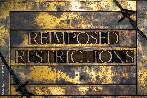 Reimposed Restrictions text formed with real authentic typeset letters on vintage textured silver grunge copper and gold background photo