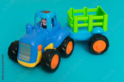 Toy blue tractor with a trailer on a blue background.Close-up.