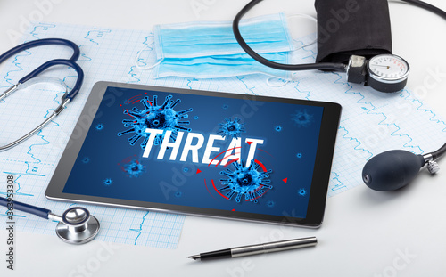 Tablet pc and doctor tools on white surface with THREAT inscription, pandemic concept