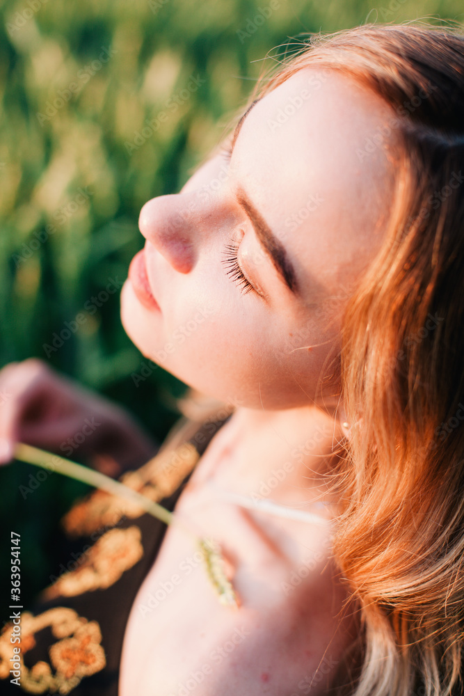 Young, slender girl embroidered dress in a large wheat field at sunset Young, slender girl embroidered dress in a large wheat field at sunset