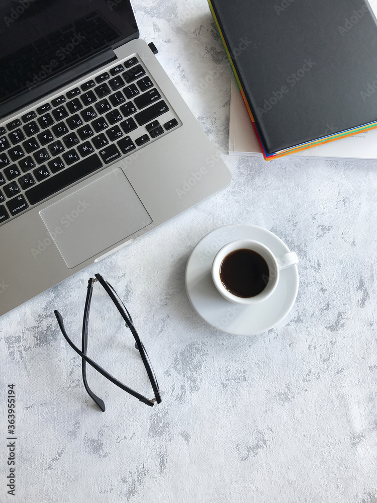 on the table is a laptop, next to glasses, a pencil and a diary. White background