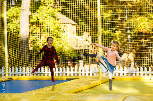 two little girls jumping on a trampoline at an autumn fair