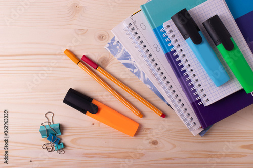 various pens and a pile of notebooks on the wooden backgrounds