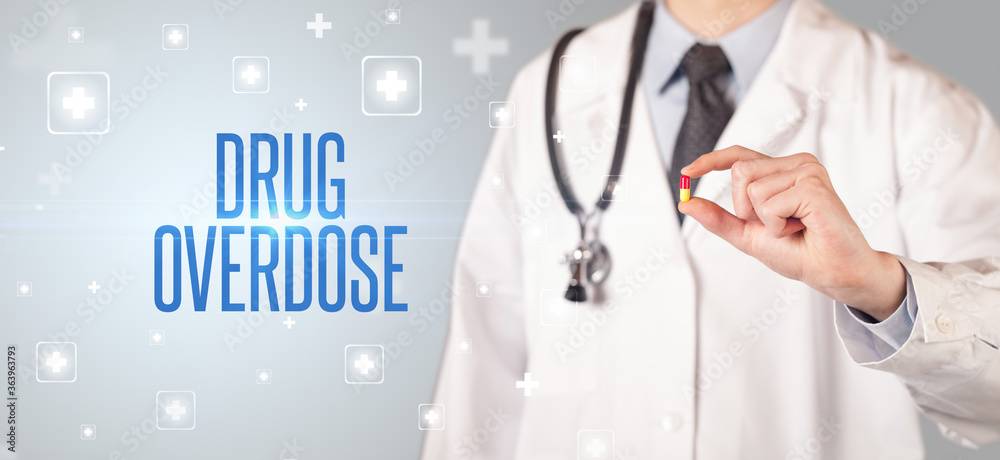 Close-up of a doctor giving a pill with DRUG OVERDOSE inscription, medical concept Close-up of a doctor giving a pill with DRUG OVERDOSE inscription, medical concept