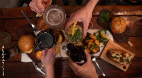 Dinner table with baked potatoes,burgers, sauces, beer and wine