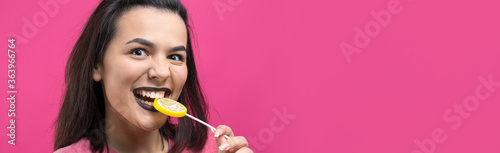 Portrait of lovely sweet beautiful cheerful woman with straight brown hair holding a lollipop near the eyes.