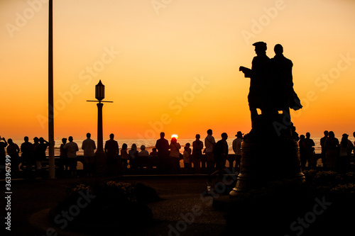 Crowd of people watching sunset at Seaside, Oregon at the turnaround. Historically the Turnaround is where Lewis & Clark ended their journey.