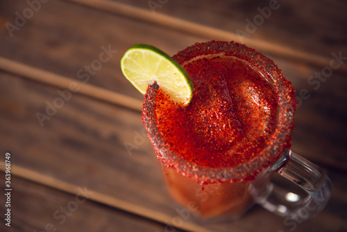 Michelada beer with tomato juice. Clamato with beer on wooden table. Mexican drink.
