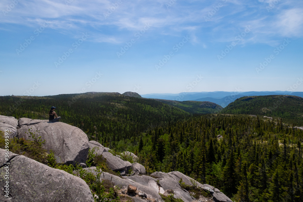 Fototapeta premium Young woman sitting in the Grands-Jardins national park, Canada 