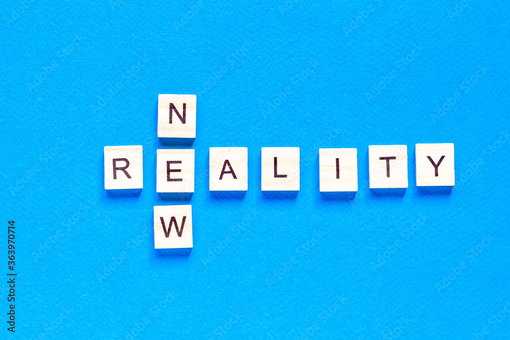 Obraz premium NOWA RZECZYWISTOŚĆ. słowa nowa rzeczywistość są zapisane drewnianymi literami na niebieskim tle. płaski układ. widok z góry