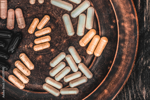 Multivitamin pills on a clay plate, on a vintage wooden table