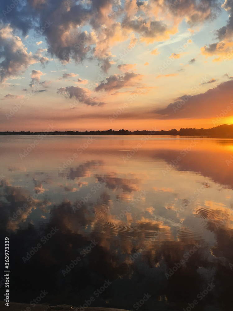 Beautiful bright and colorful summer sunset reflection with clouds