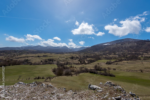 Landscape of green fields with mountains in the background and blue skies in the province of L'Aquila in the Abruzzo region of Italy.