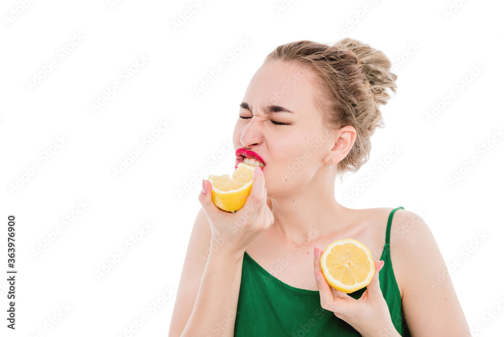 Emotional portrait of a beautiful girl on an isolated white background who is eating a lemon. The concept of a healthy diet, healthy lifestyle and vegetarianism Emotional portrait of a beautiful girl on an isolated white background who is eating a lemon. The concept of a healthy diet, healthy lifestyle and vegetarianism